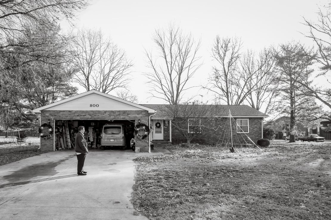 a black and white photo of a person standing in front of an open garage