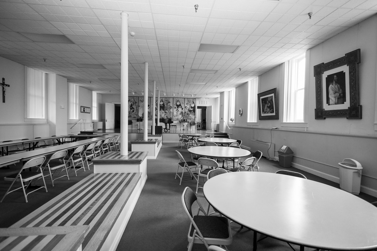 a black and white photo of a decorated religious cafeteria with tables and chairs