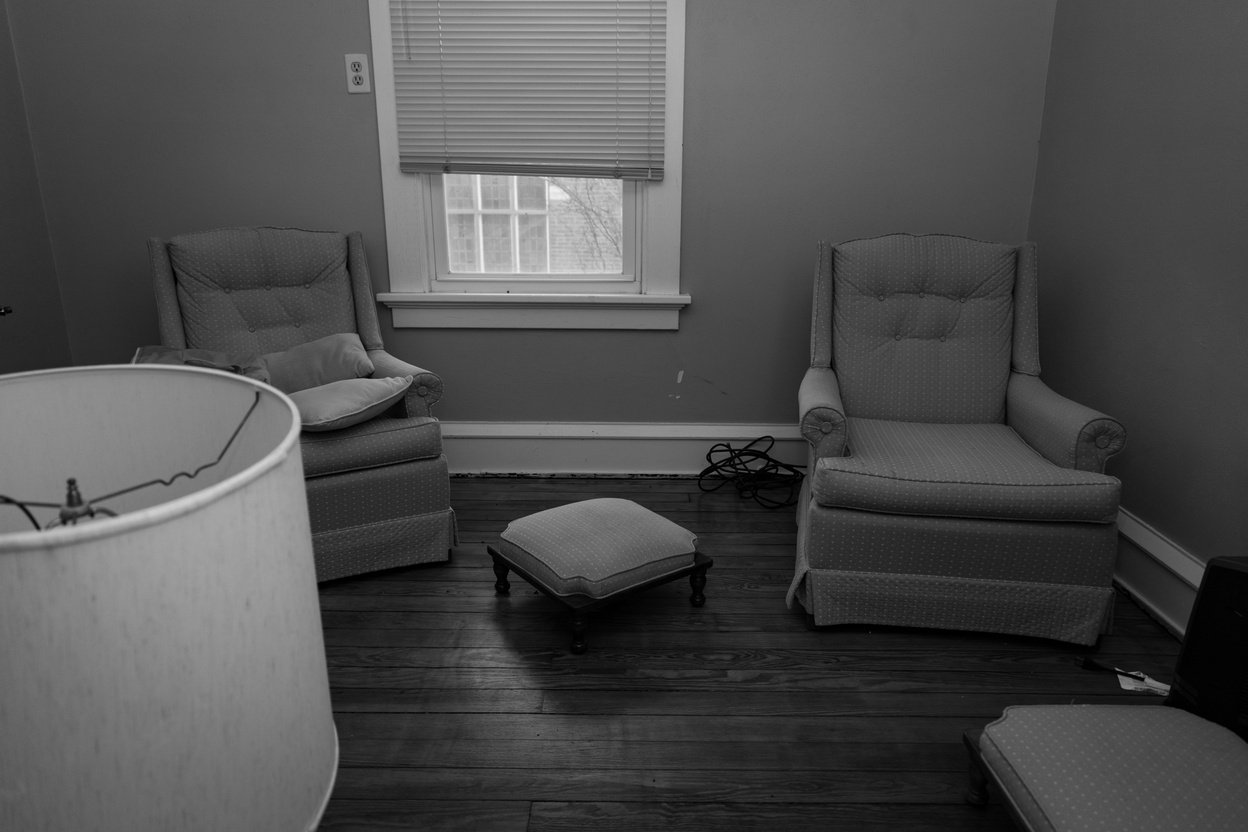 a black and white photo of a room with two chairs and a lamp