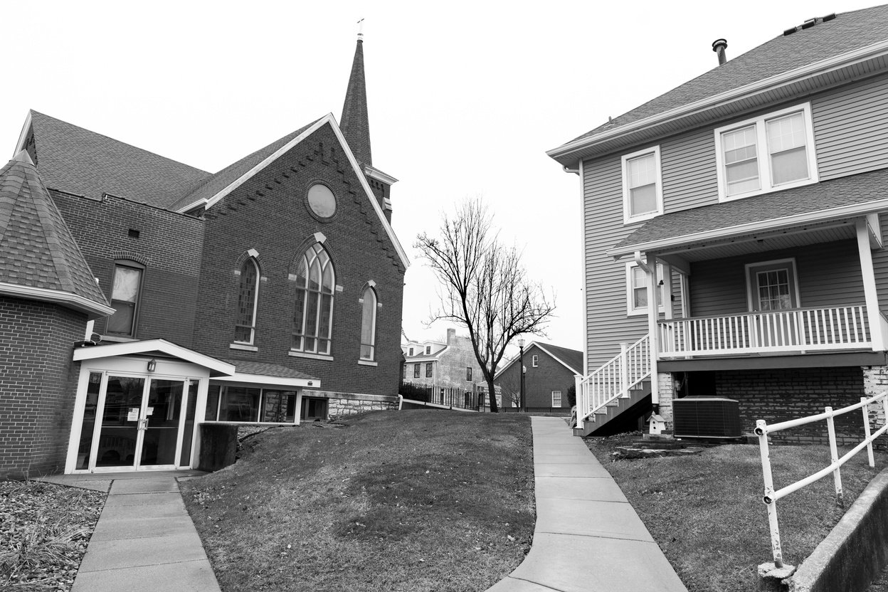 a black and white photo of a church next door to a residential home