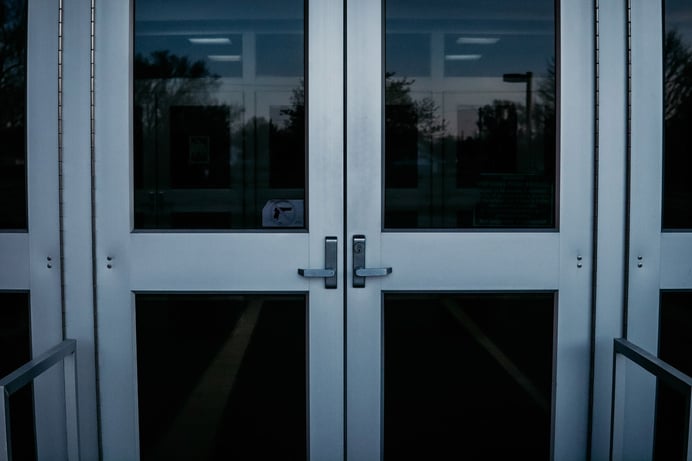 two entrance doors to a building with a no weapons sign