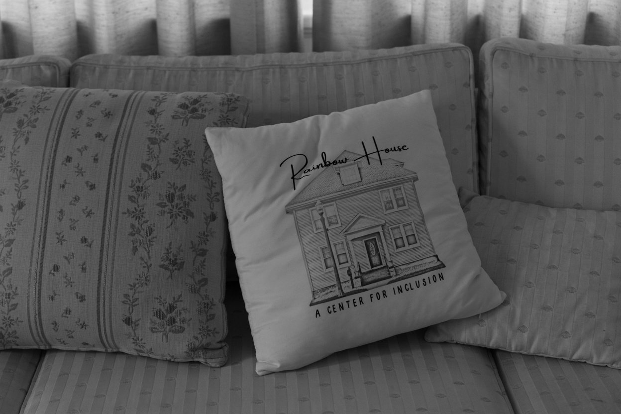 a black and white photo of a pillow that says 
"Rainbow House" on a couch