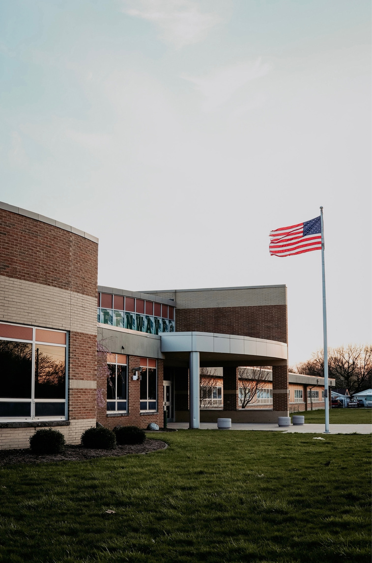 a school building with an american flag flying in front of it