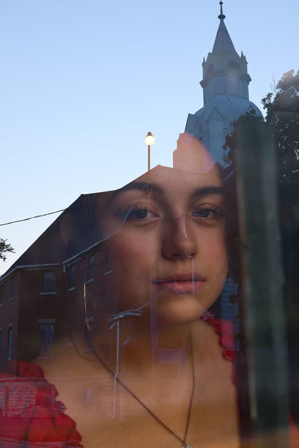 a reflection of a person in a window with a church in the background